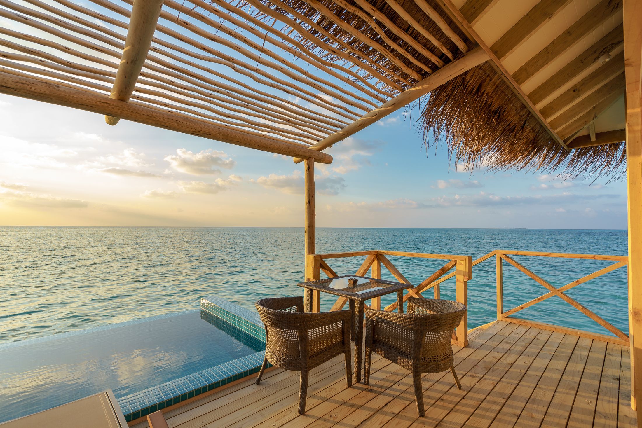 A shaded deck with a dining table over the water
