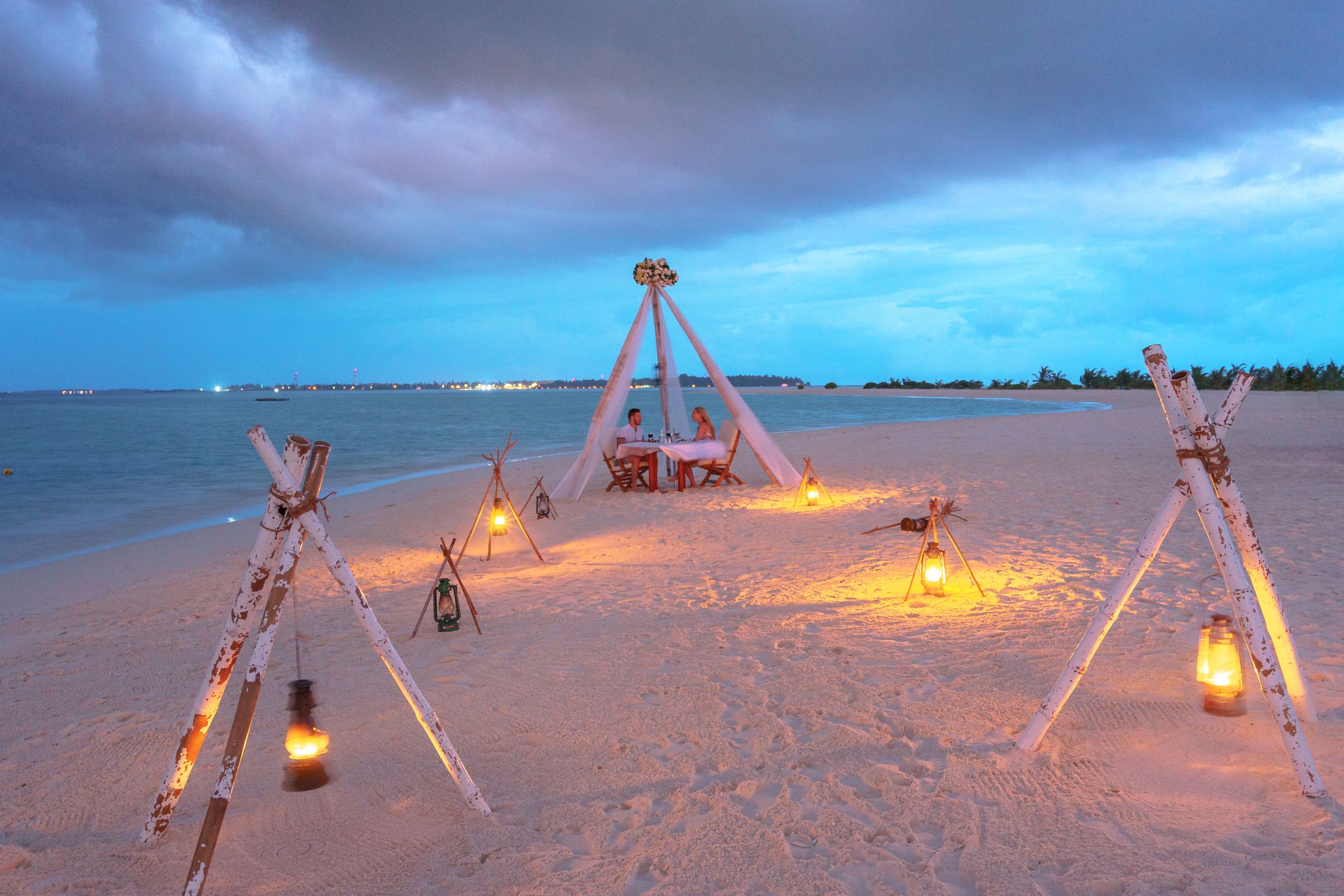 A candlelit table for two on the sand